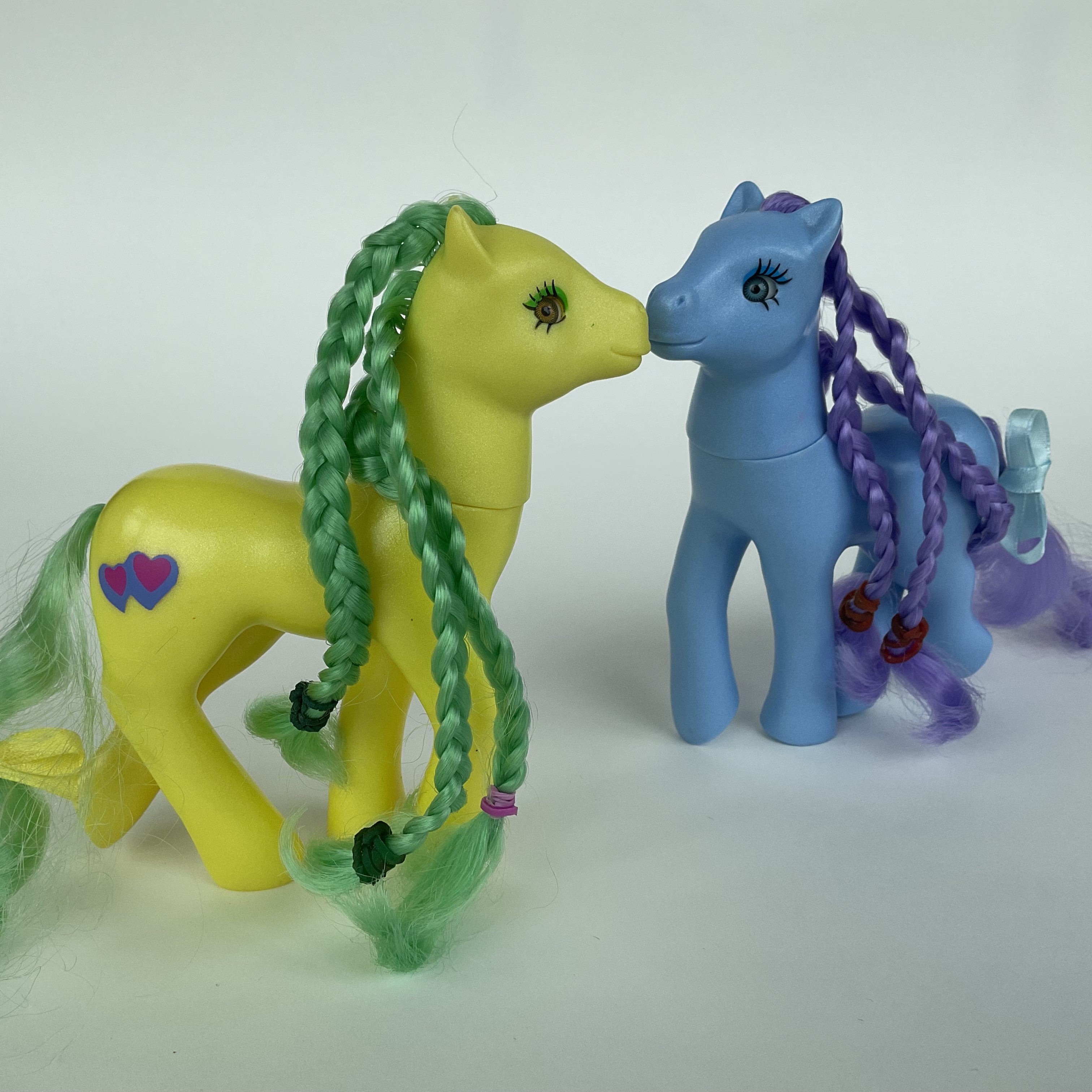 2 søde ponyfigurer med flettet hår – gul/grøn og blå/lilla – ca. 14 cm