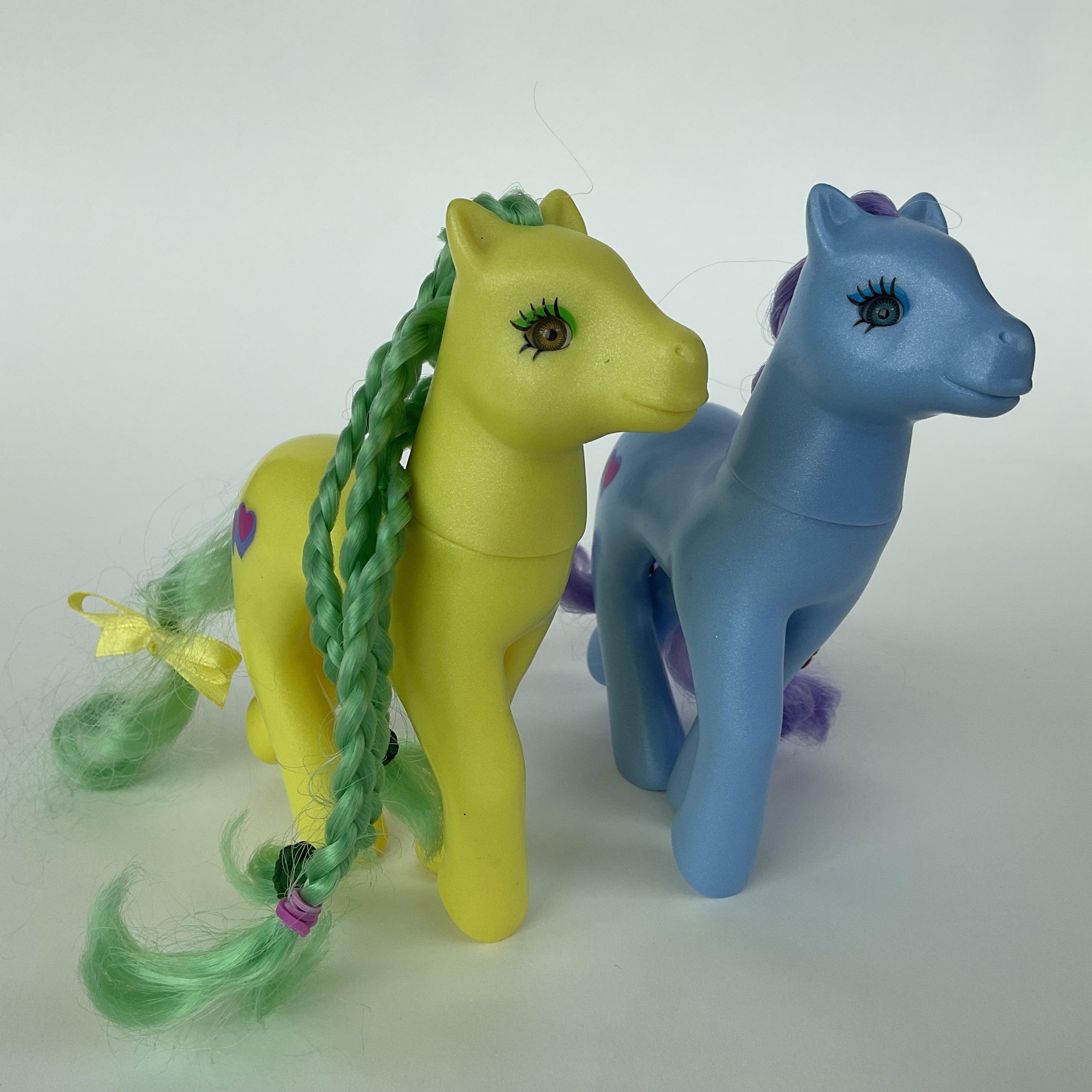 2 søde ponyfigurer med flettet hår – gul/grøn og blå/lilla – ca. 14 cm