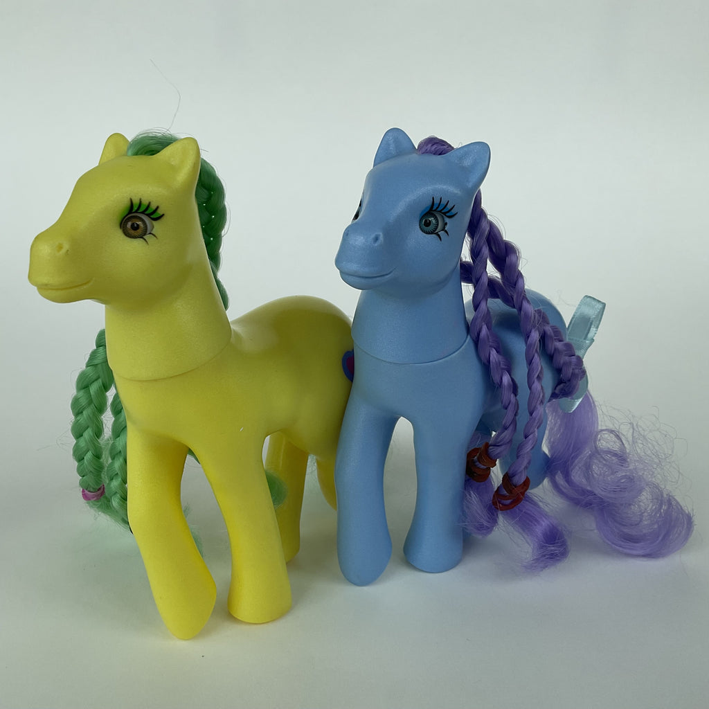 2 søde ponyfigurer med flettet hår – gul/grøn og blå/lilla – ca. 14 cm