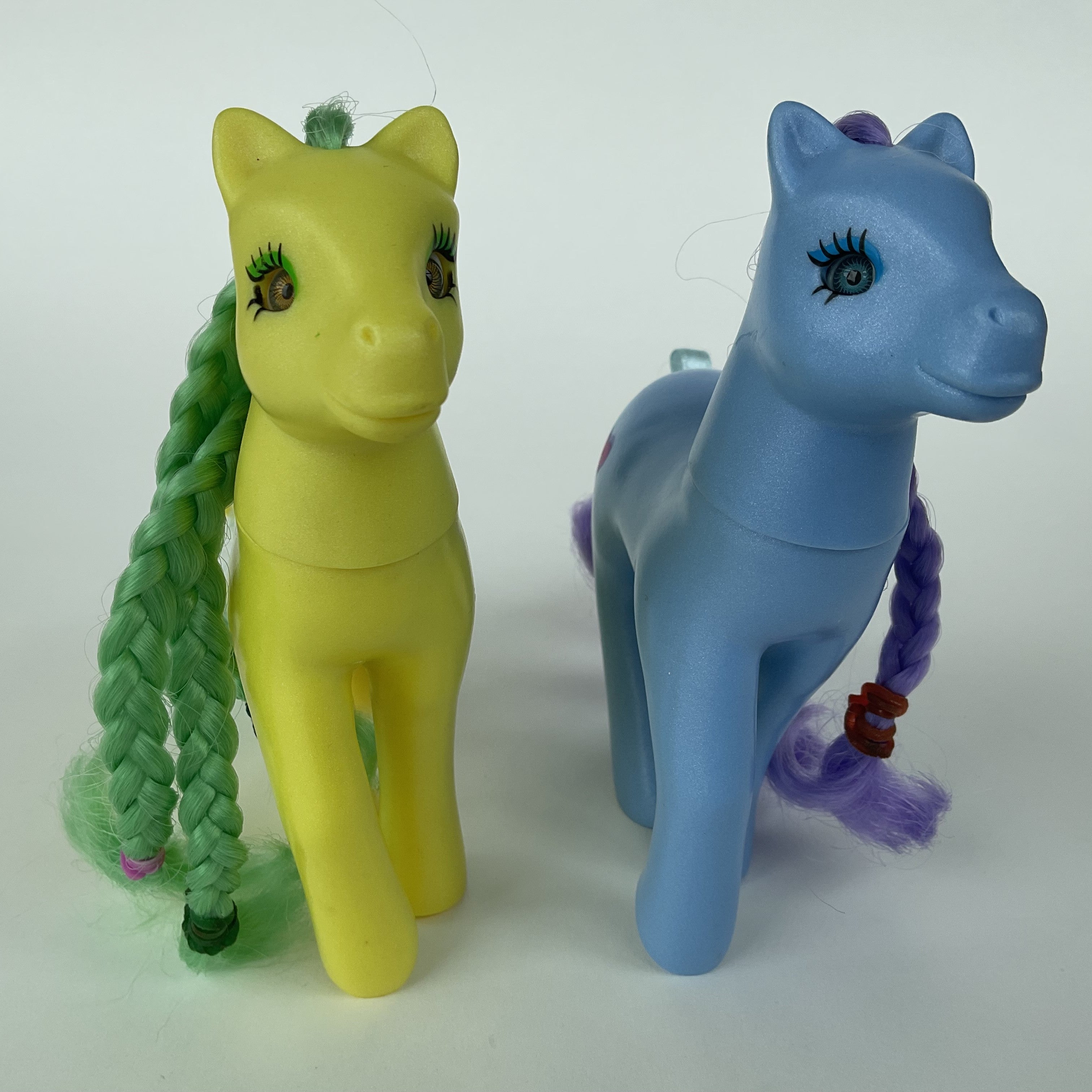 2 søde ponyfigurer med flettet hår – gul/grøn og blå/lilla – ca. 14 cm