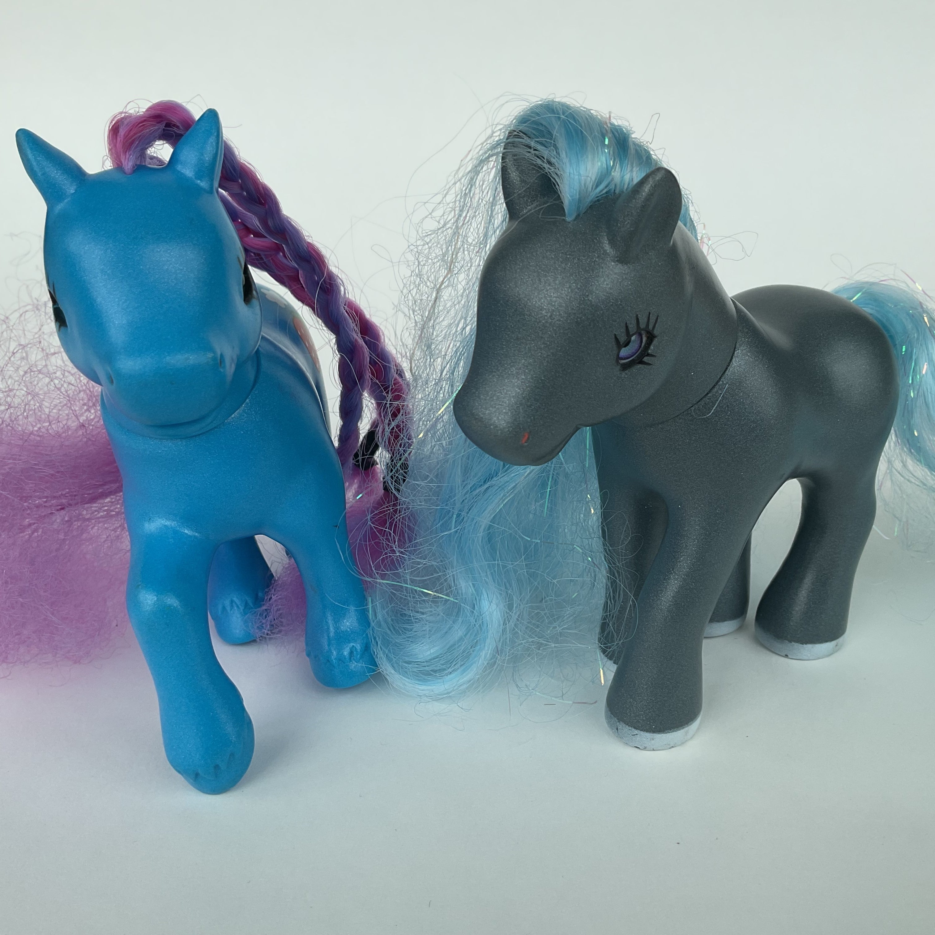 2 flotte ponyfigurer med farverigt hår – blå/lilla og grå/blå – ca. 14 cm