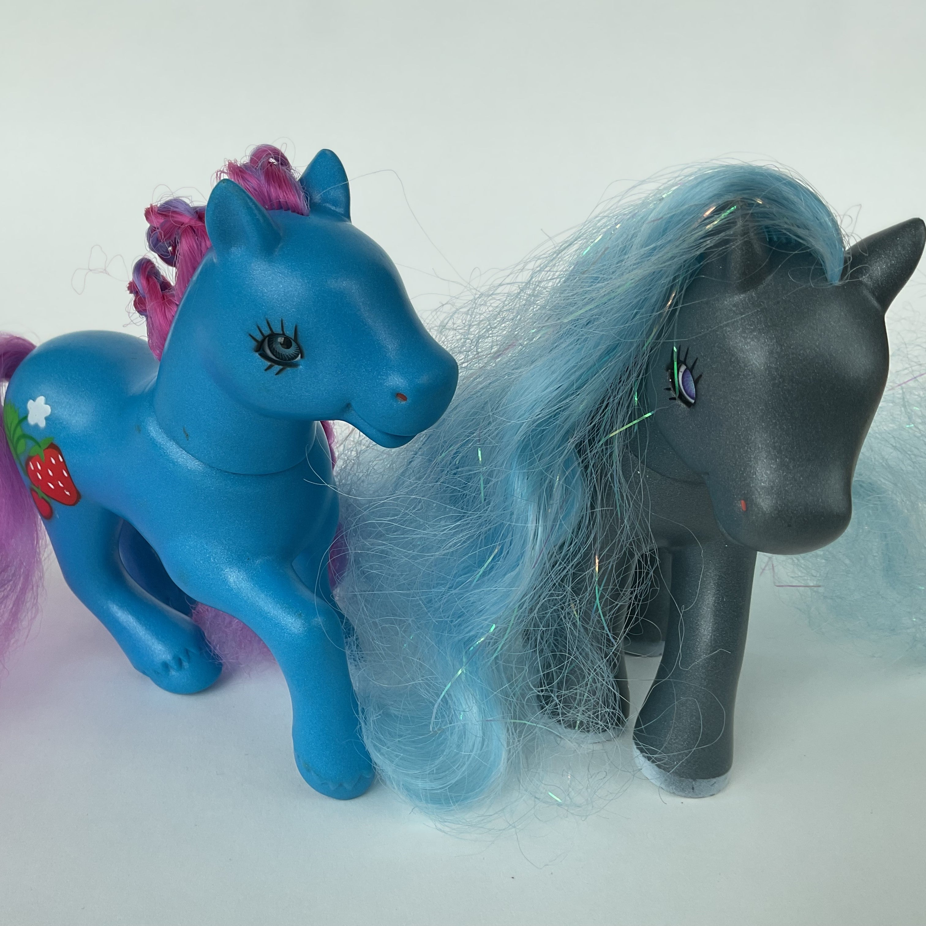 2 flotte ponyfigurer med farverigt hår – blå/lilla og grå/blå – ca. 14 cm