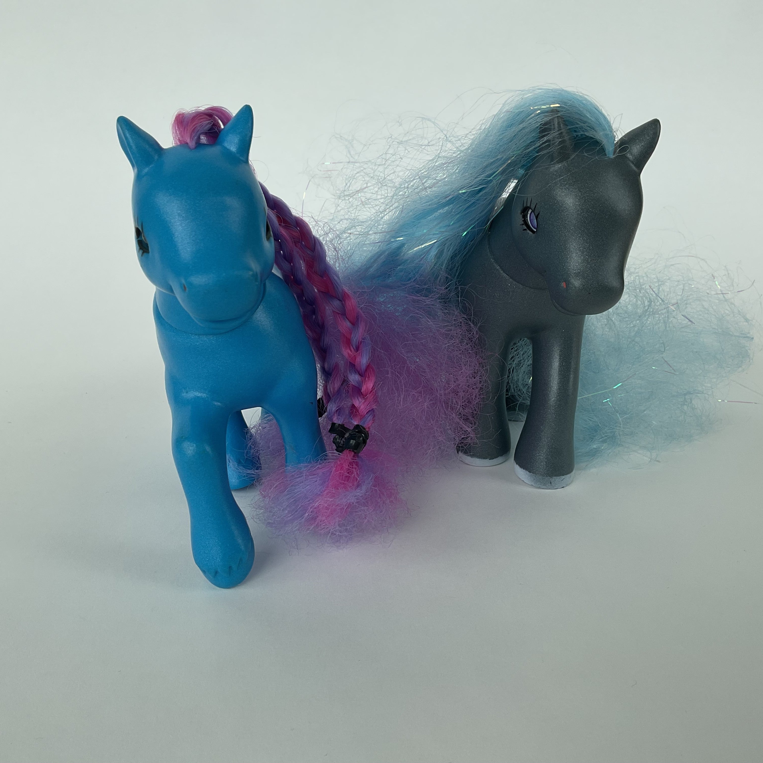 2 flotte ponyfigurer med farverigt hår – blå/lilla og grå/blå – ca. 14 cm