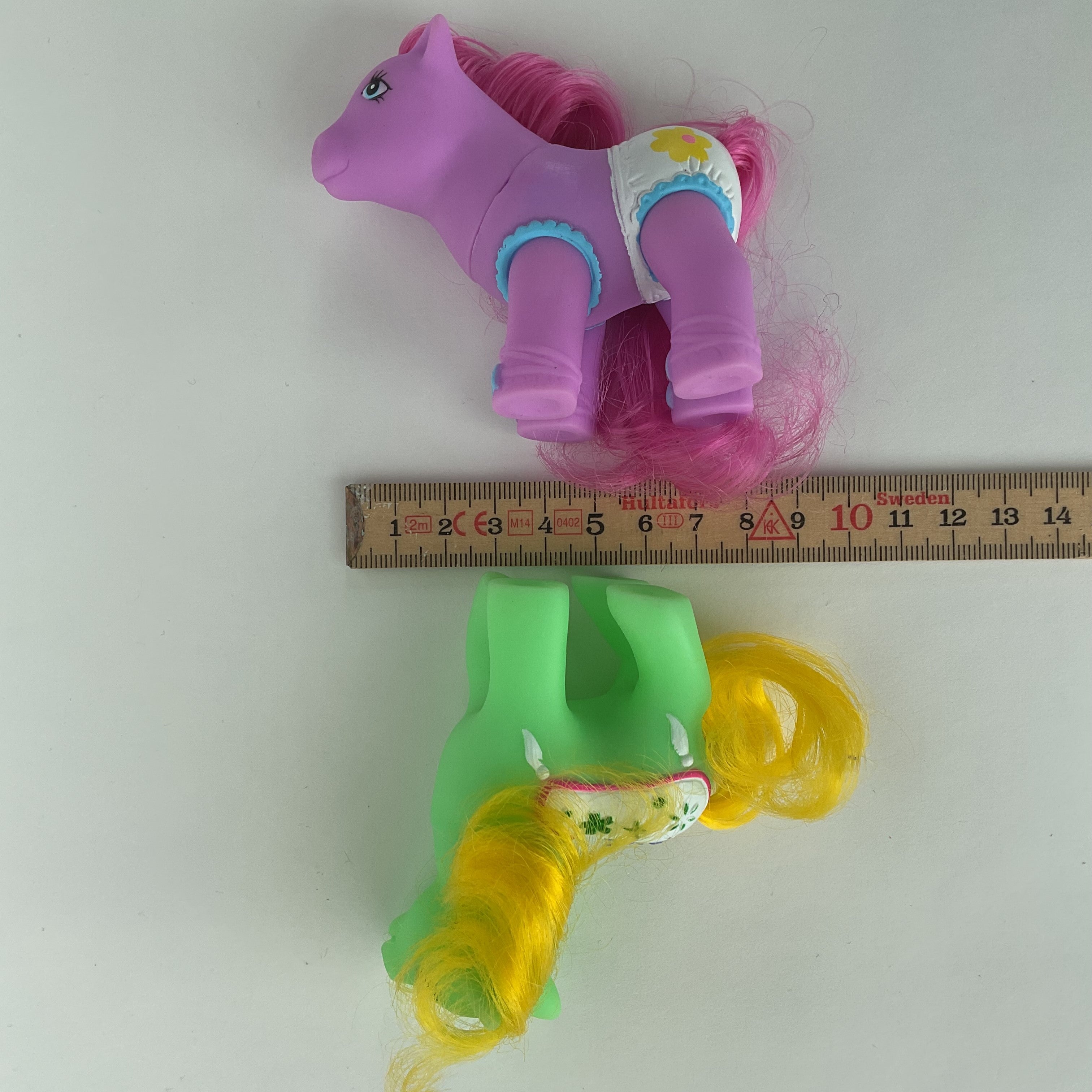 2 søde ponyfigurer med farverige detaljer – grøn/gul og lilla/pink – ca. 9 cm
