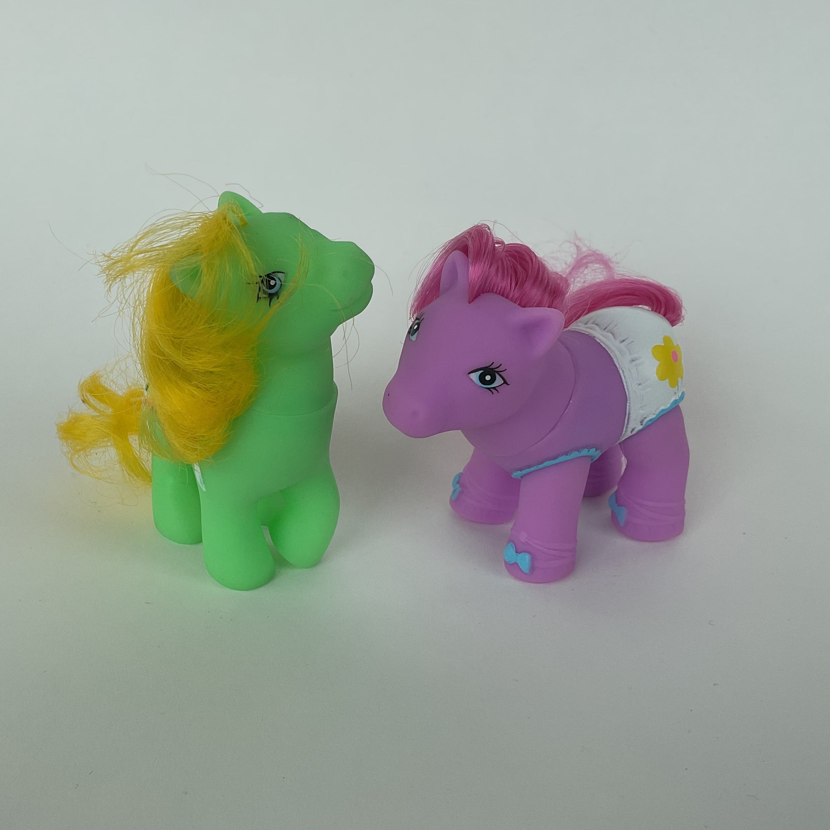2 søde ponyfigurer med farverige detaljer – grøn/gul og lilla/pink – ca. 9 cm