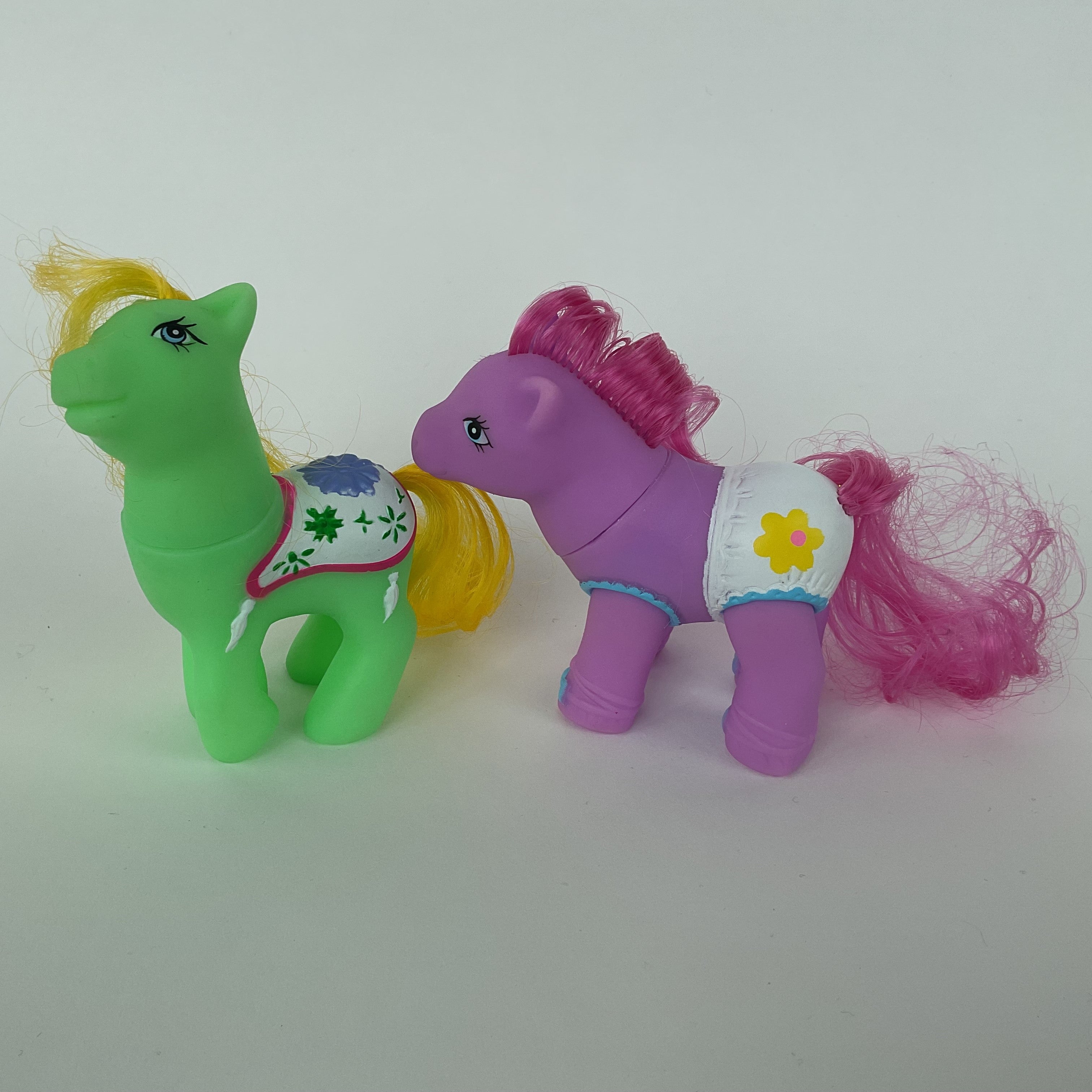 2 søde ponyfigurer med farverige detaljer – grøn/gul og lilla/pink – ca. 9 cm