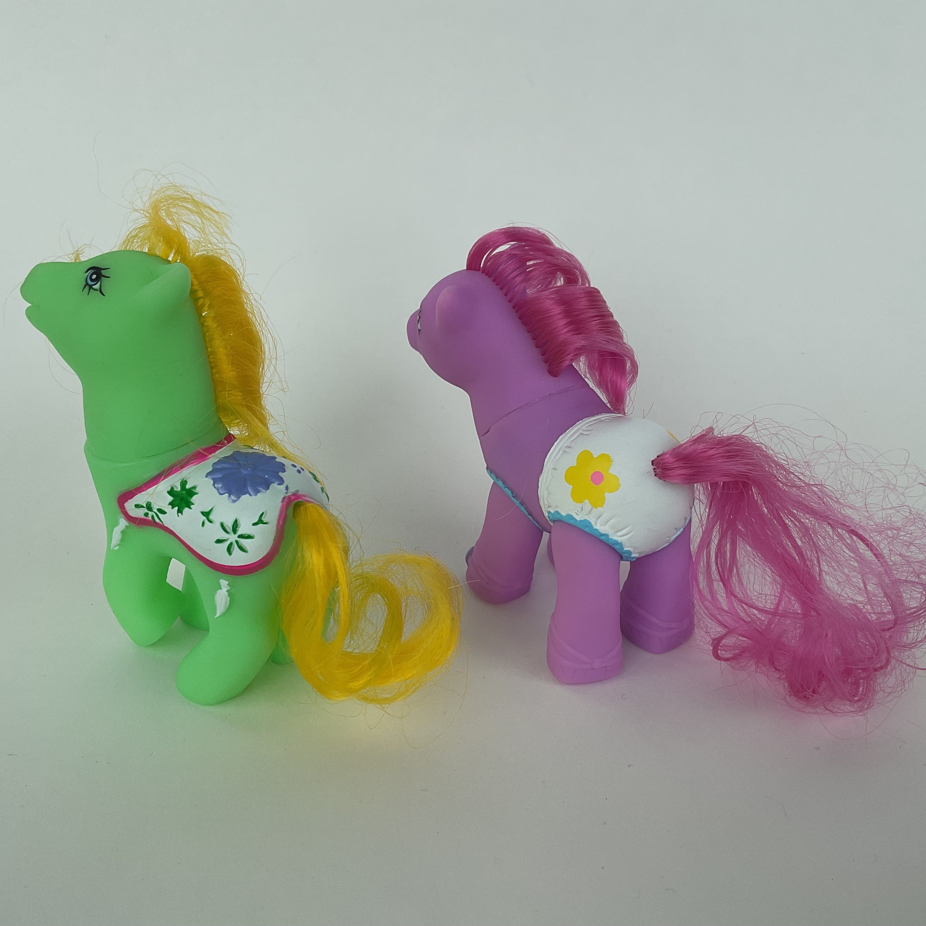 2 søde ponyfigurer med farverige detaljer – grøn/gul og lilla/pink – ca. 9 cm