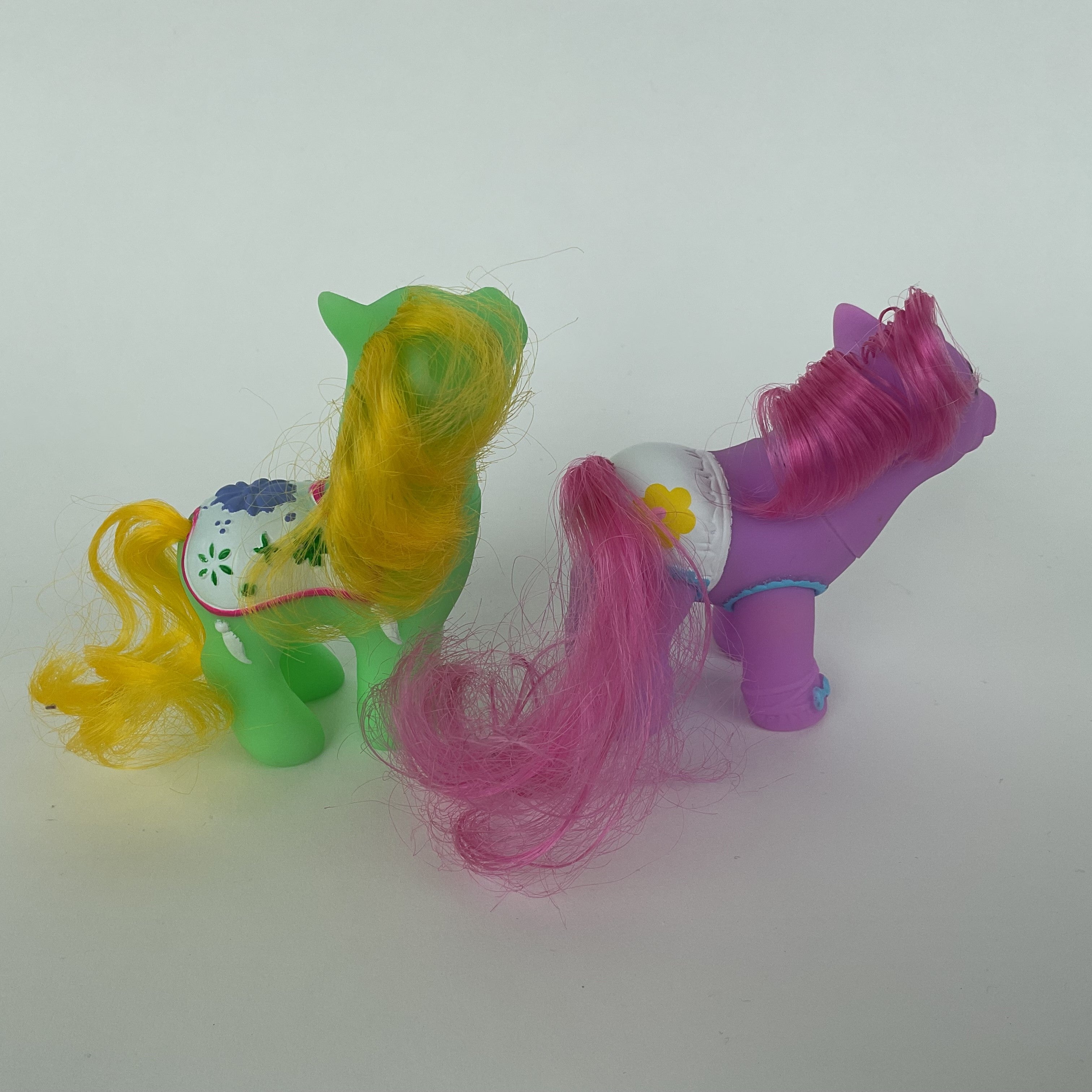 2 søde ponyfigurer med farverige detaljer – grøn/gul og lilla/pink – ca. 9 cm