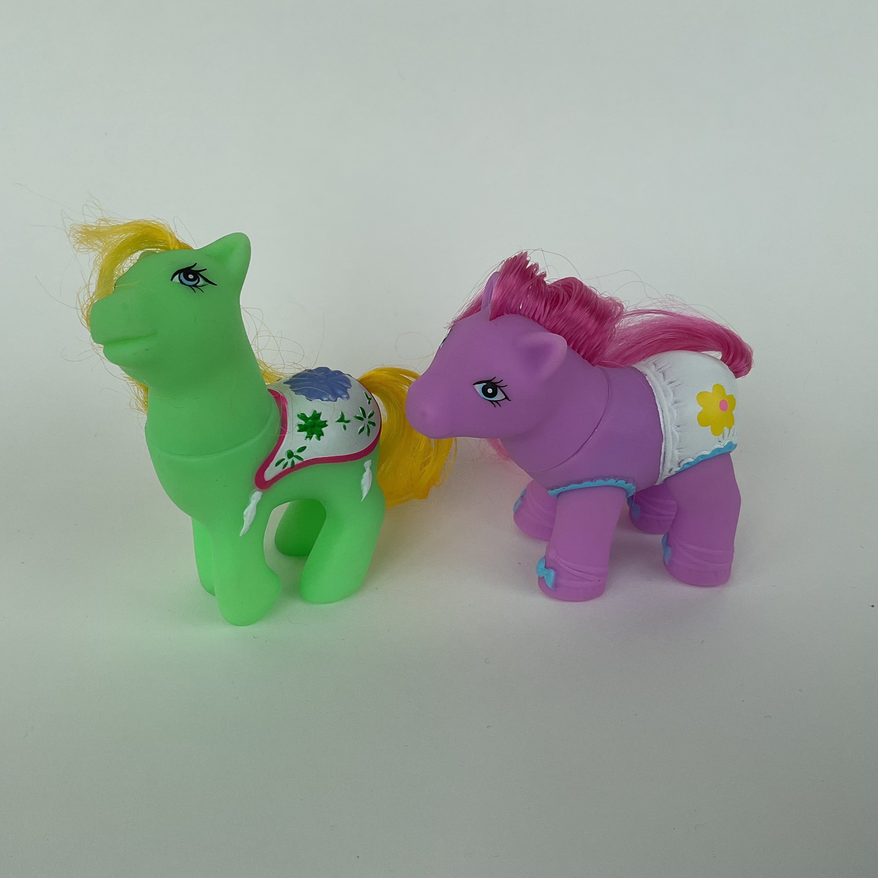 2 søde ponyfigurer med farverige detaljer – grøn/gul og lilla/pink – ca. 9 cm